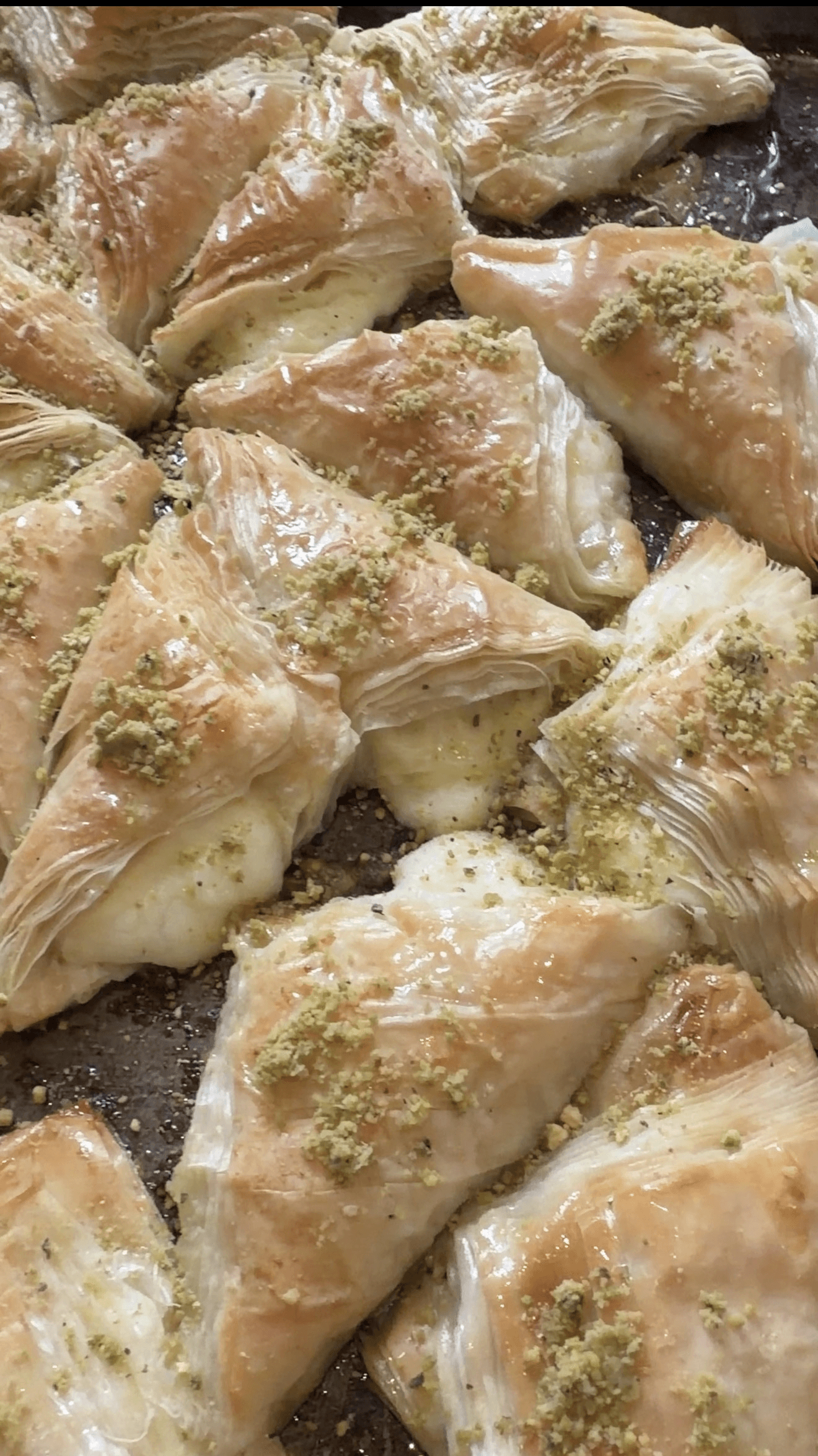 Golden phyllo baklava triangles topped with crushed pistachios