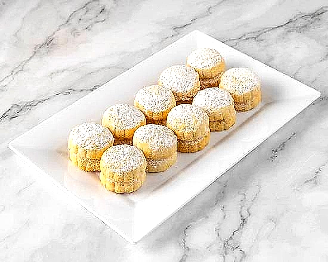 A dozen Alhana date maamoul cookies on a white plate